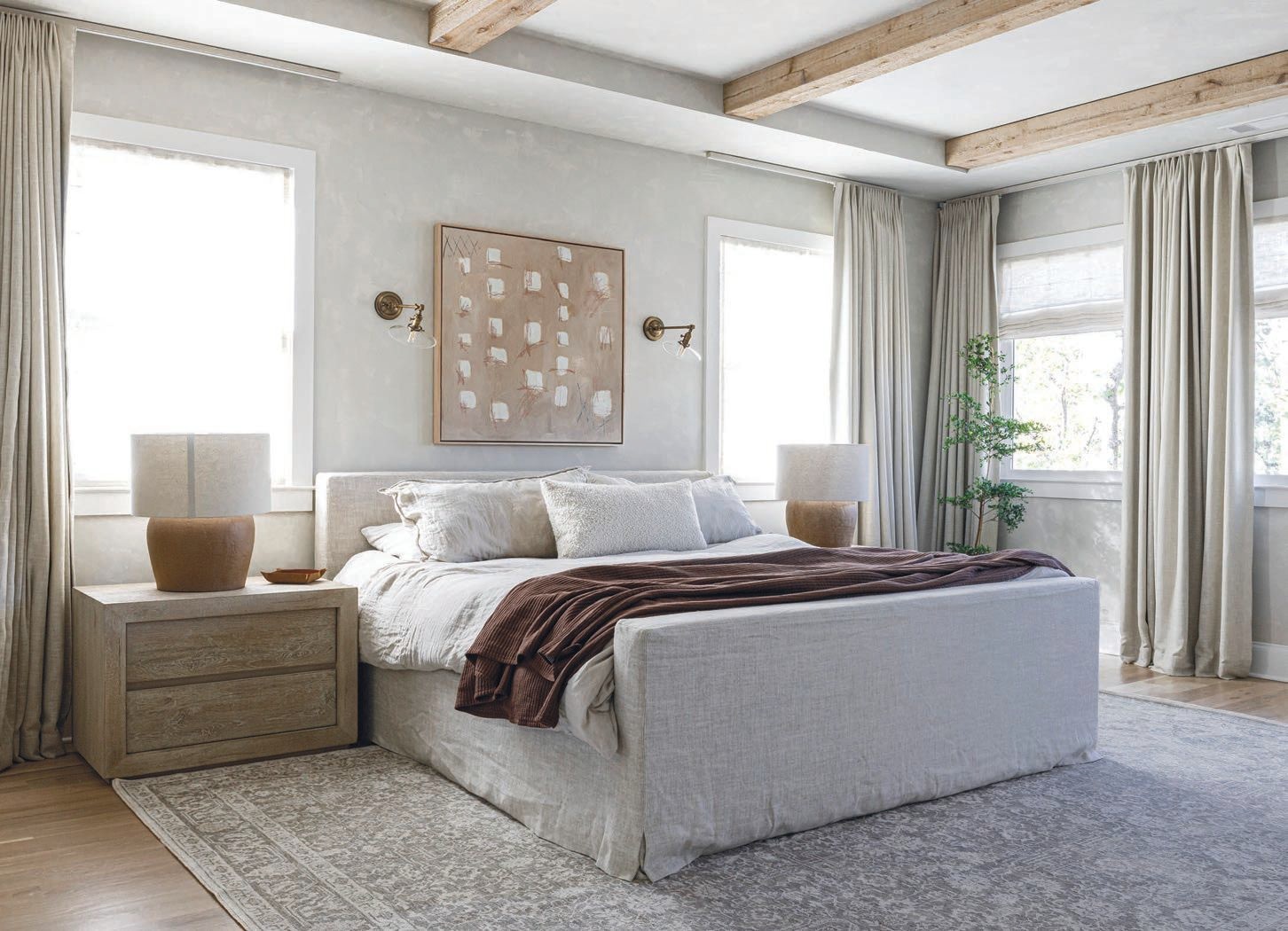 The primary bedroom features Jim Davis Designs window treatments (as does the rest of the home) paired with a neutral, textured paint by Portola Paints Photographed by Samantha Wittman